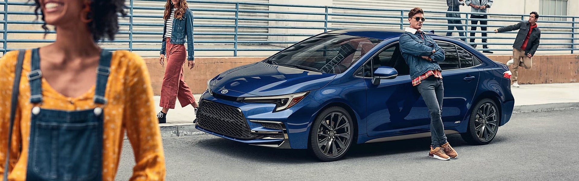 two people in front of a blue Toyota Corolla Hybrid